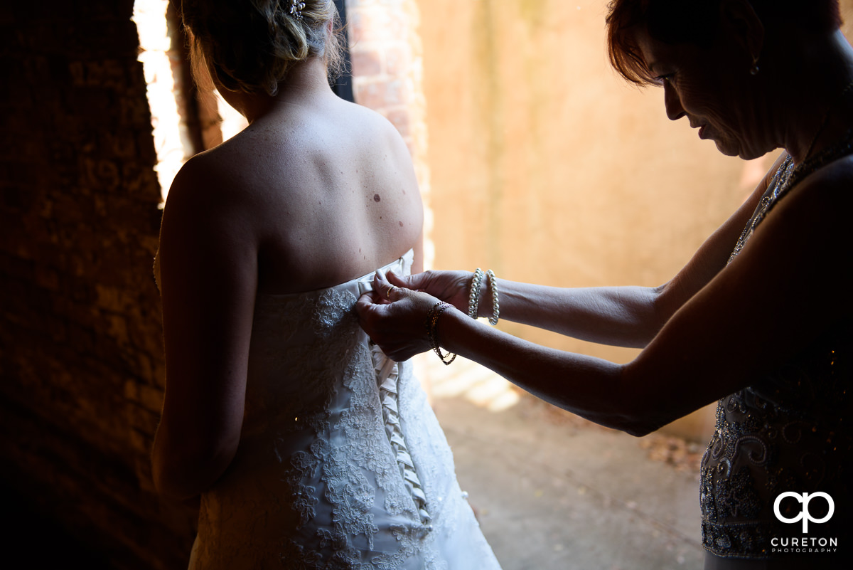 Bride getting her dress zipped up.