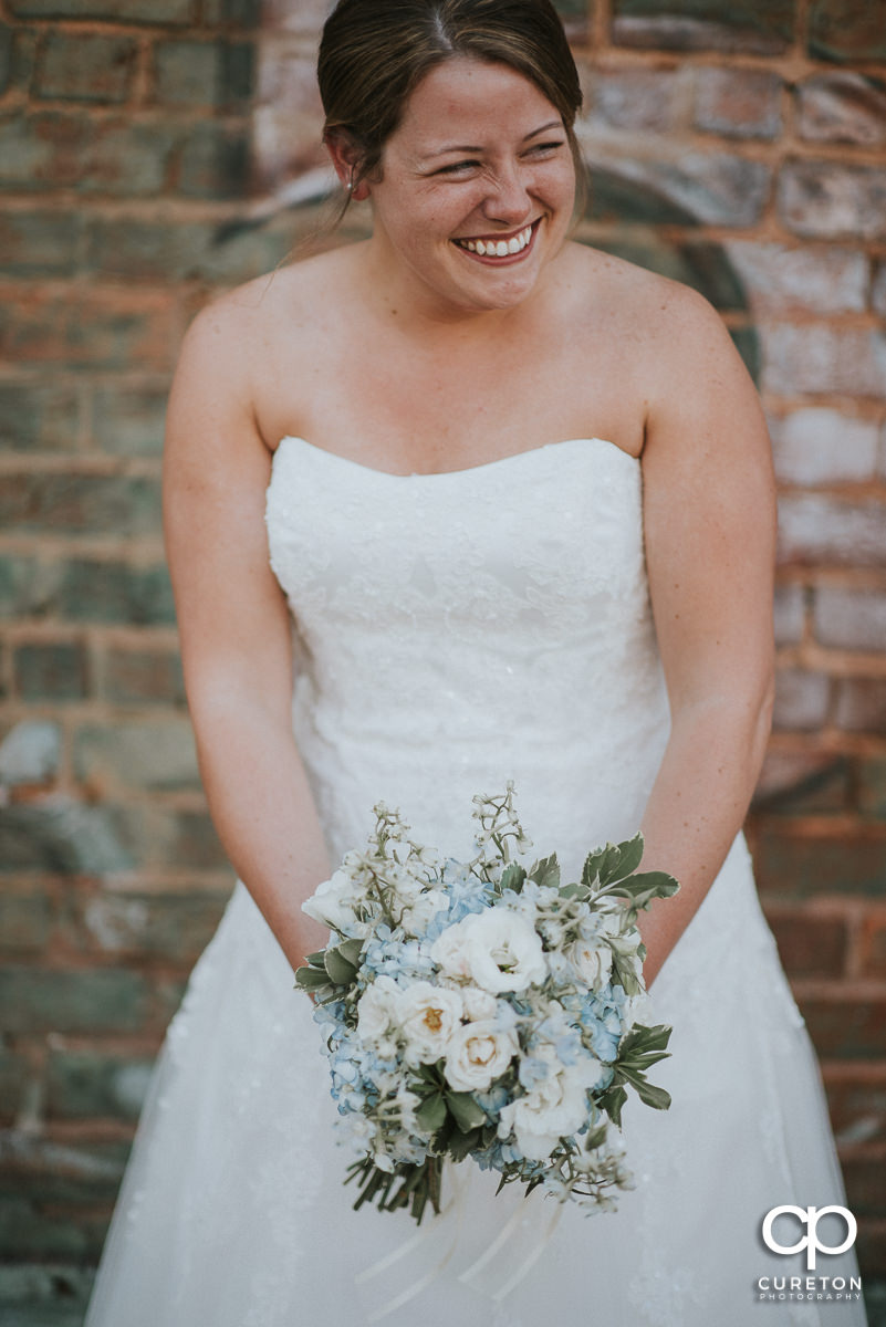 Bride laughing while holding a beautiful bouquet.