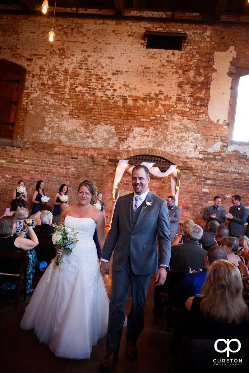 Bride and groom walking down the aisle at The Old Cigar Warehouse.