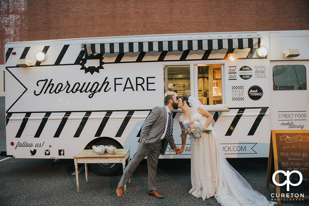 Bride and Groom kissing in front of the Thorough Fare food truck.