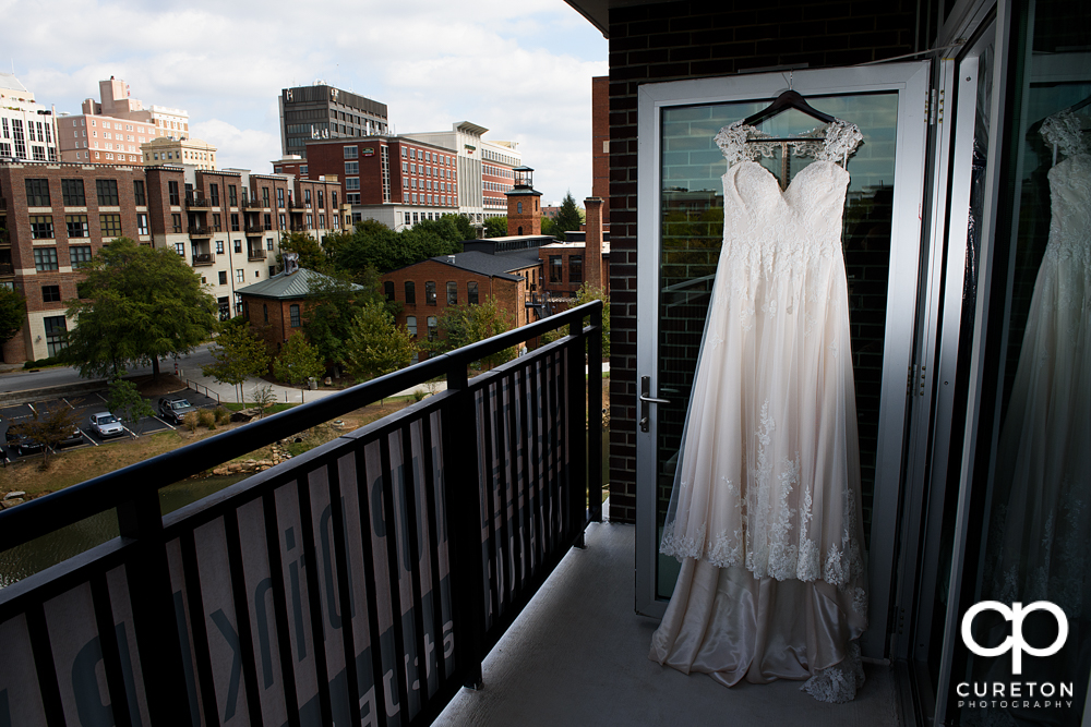 Bride's dress hanging in the window of Embassy suites overlooking downtown Greenville.