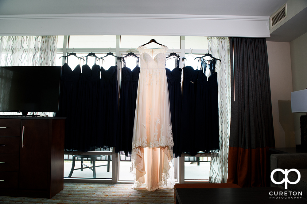Bride's dress hanging with the bridesmaids dresses.