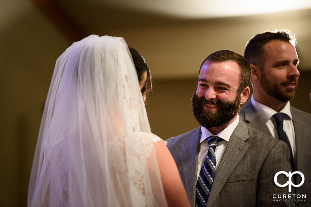 Groom smiling at his bride during the wedding ceremony.