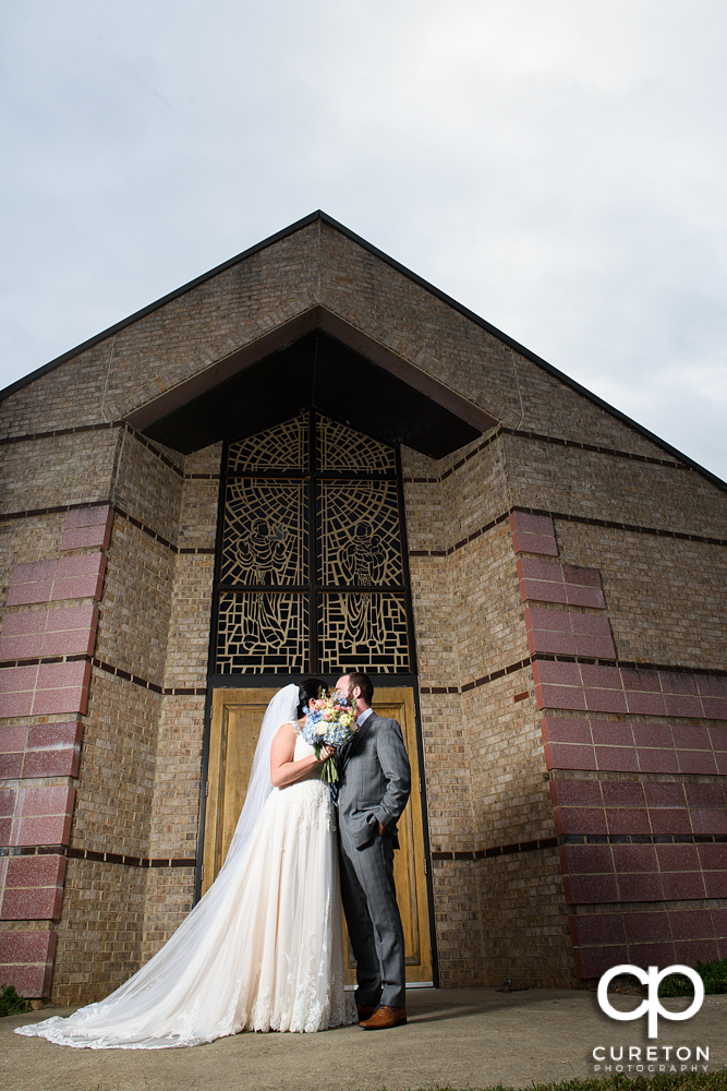 Bride and groom kissing outside of Saint Anthony's in downtown Greenville South Carolina.