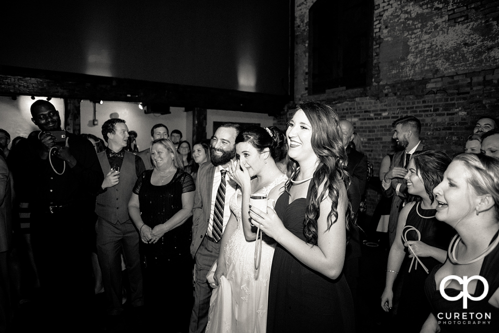 Bride and groom watching as the father of the bride gives a toast.