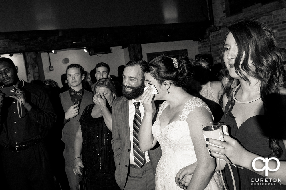 The bride tearing up as her father speaks at her wedding.