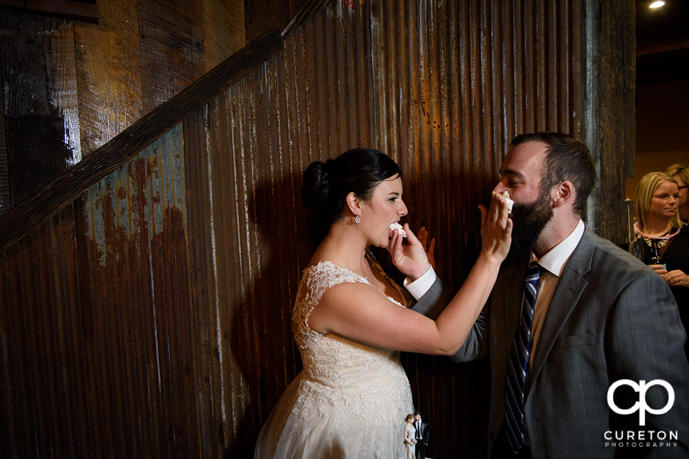 The bride and groom smashing cake on each other's face.