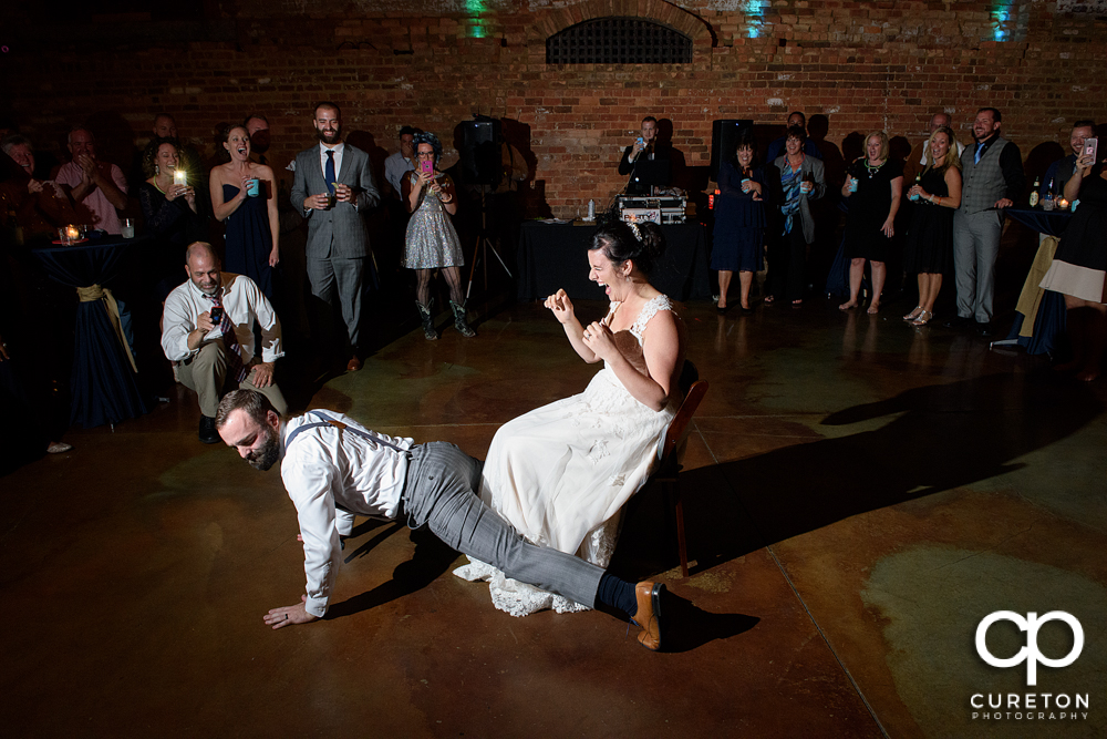 The groom dances for the bride as he takes the garter off.