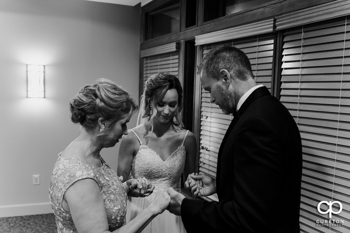 Bride praying with her family.