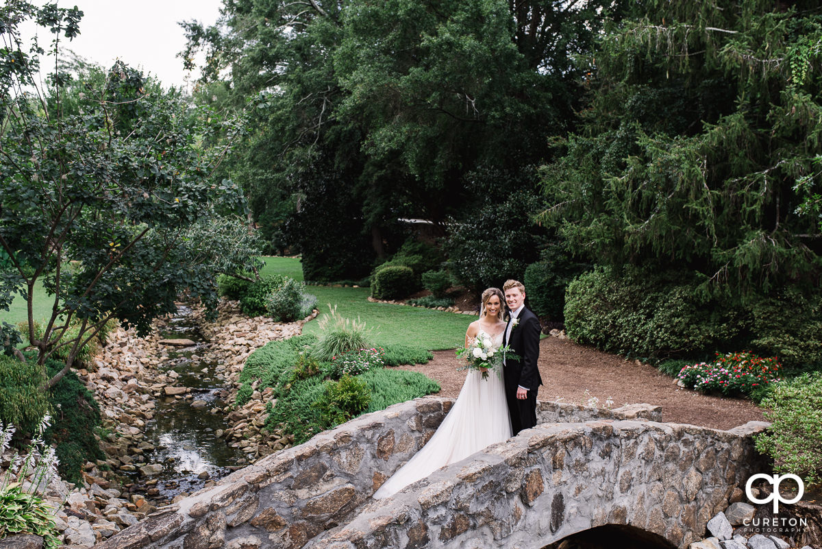 Bride and groom standing on a bridge in the Rock Quarry Garden.