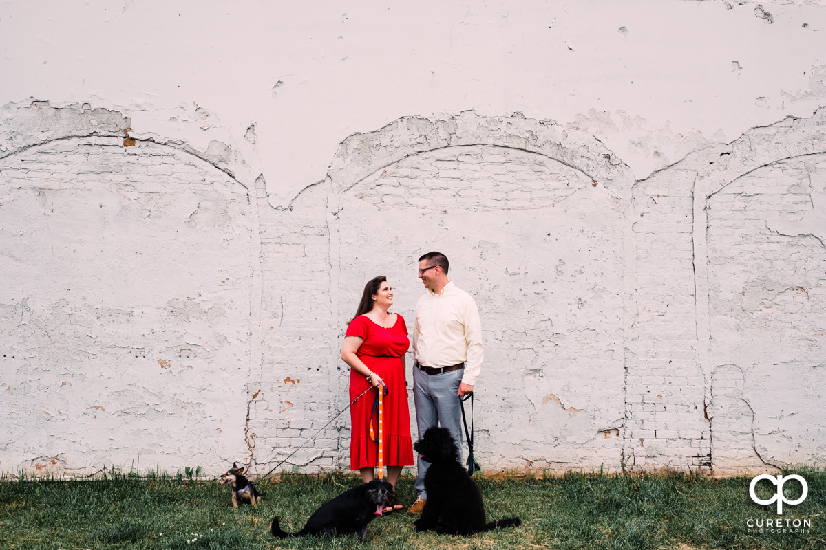 Future bride and groom walking downtown with their dogs during an engagement session in West End Greenville,SC.