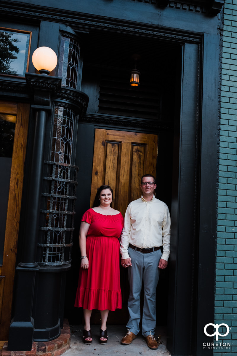 Engaged couple standing outside of Husk in downtown Greenville,SC.