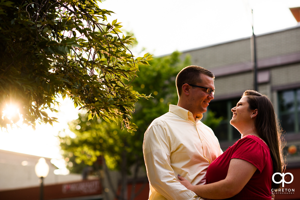Future bride and groom backlit by warm sunlight during an engagement session in West End Greenville,SC