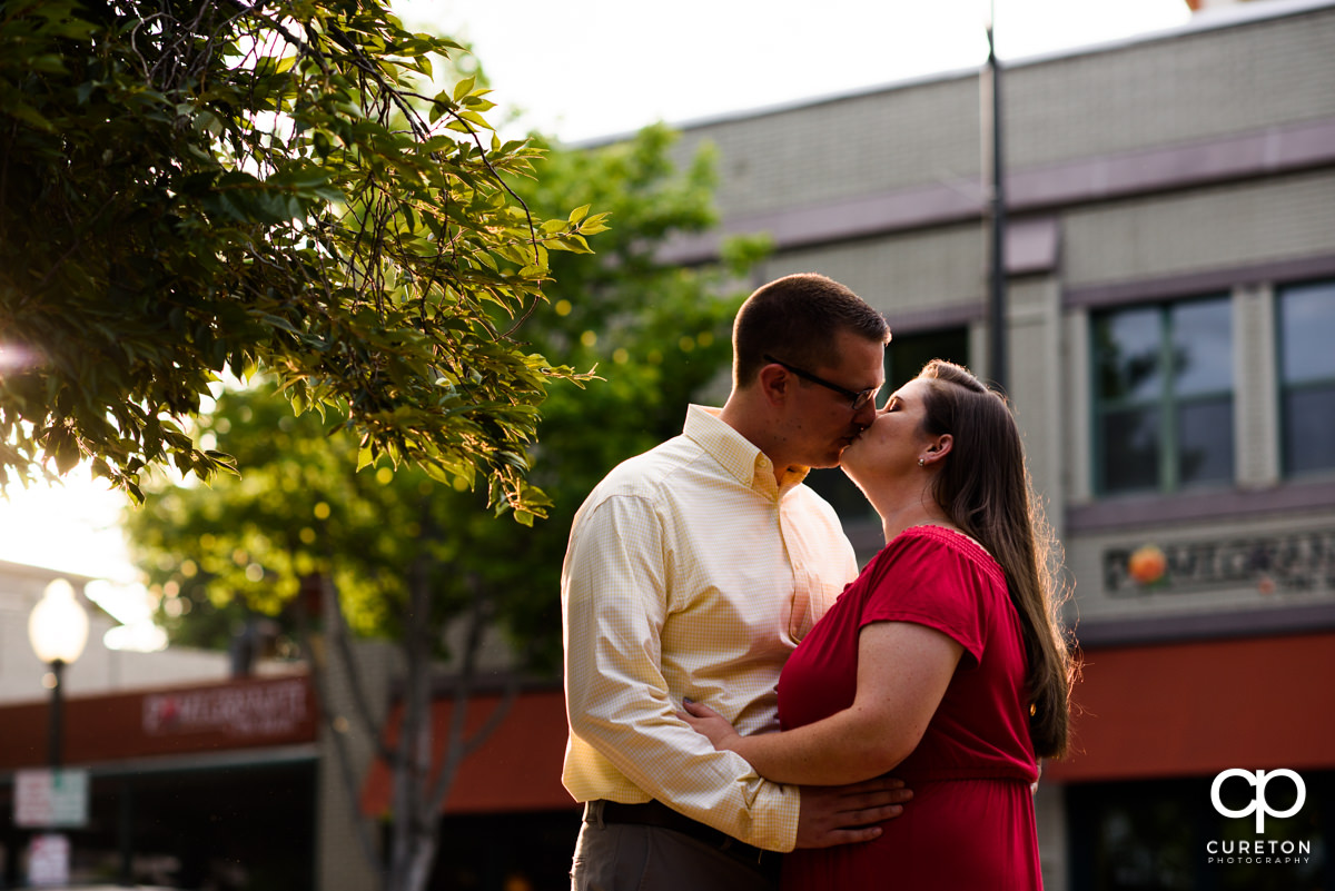 Engaged couple kissing on Main Street Greenville.