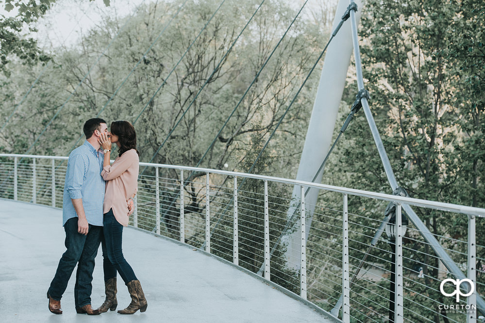 Couple kissing on Falls Park bridge.
