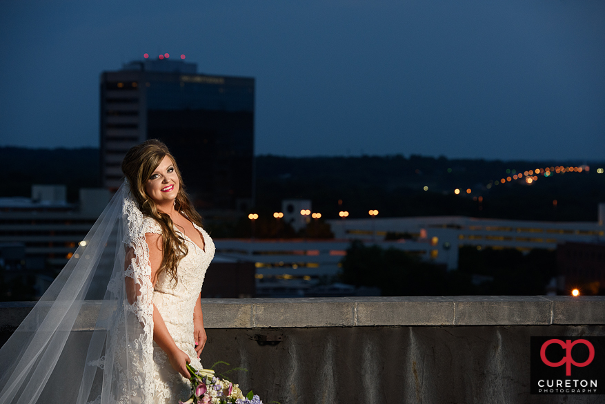Bride at twilight on a rooftop overlooking the downtown Greenville,SC skyline.