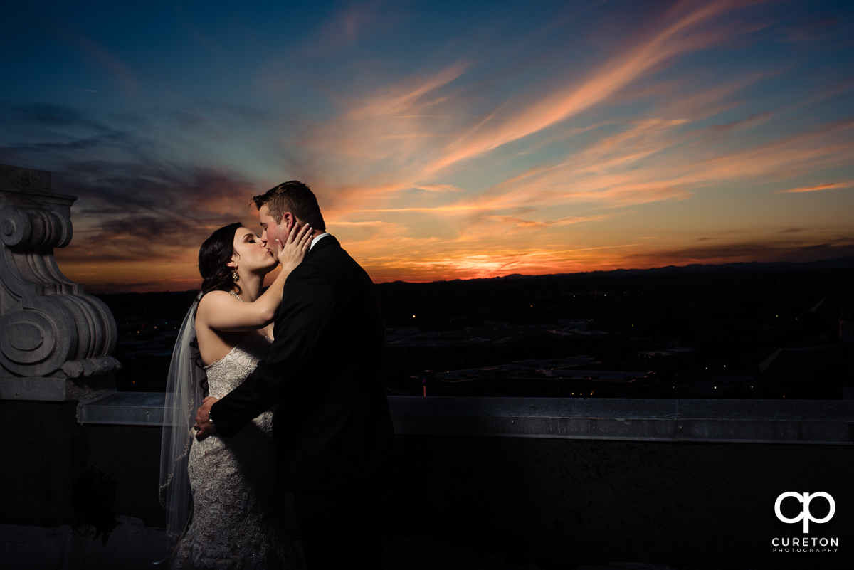 Bride kissing her groom at sunset on the rooftop at their Westin Poinsett Hotel Wedding in Greenville,SC.