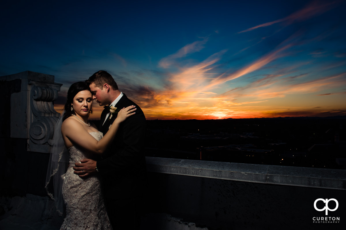Groom snuggling close to his bride on the rooftop of The Westin Poinsett Hotel in downtown Greenville,SC.