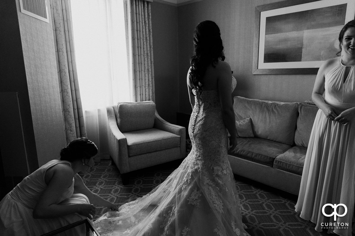 Bridesmaids helping the bride with the back of her dress.