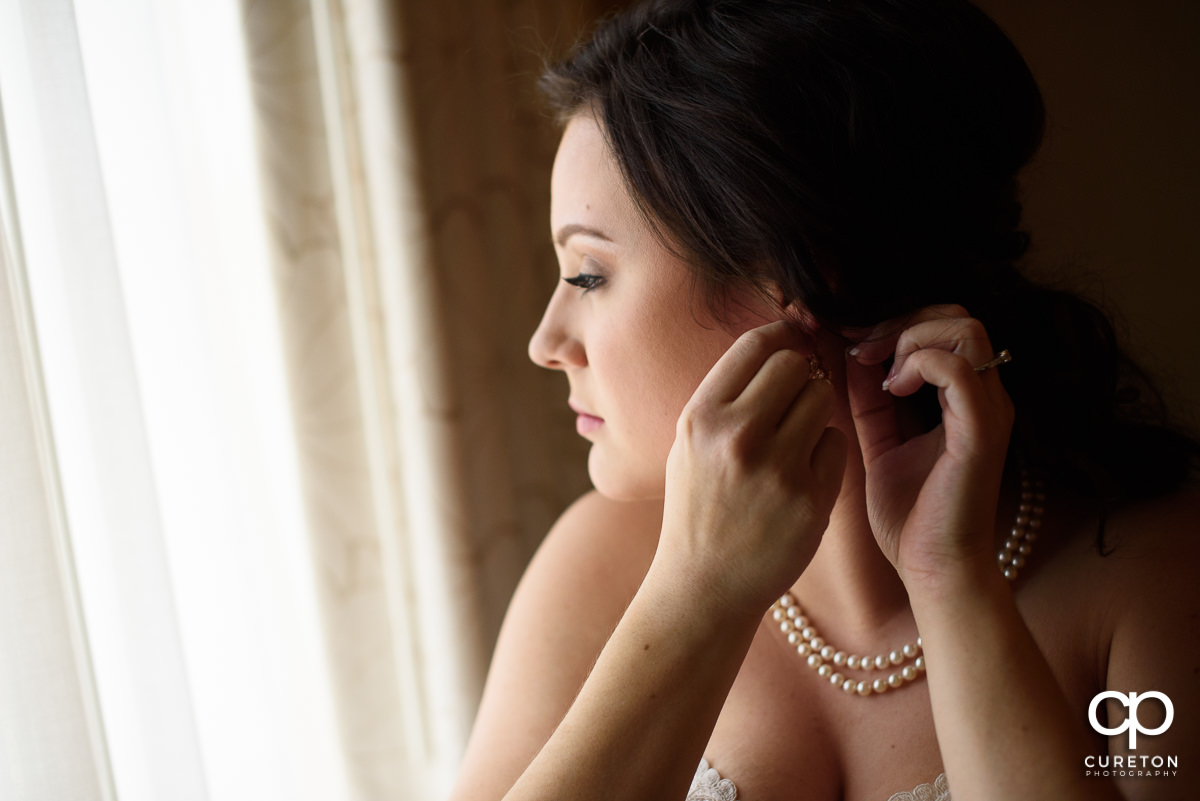 Bride putting on her earrings.