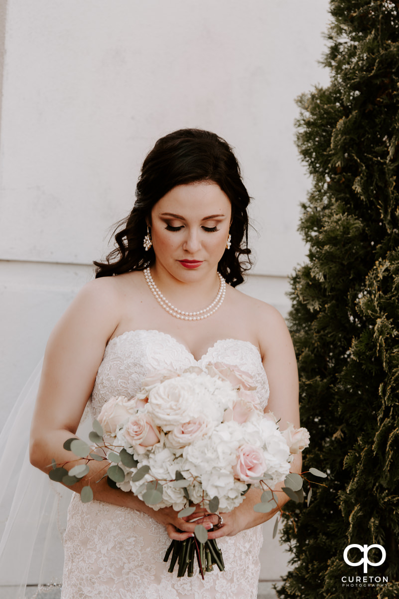 Bride standing in front of the hotel wth her bouquet.