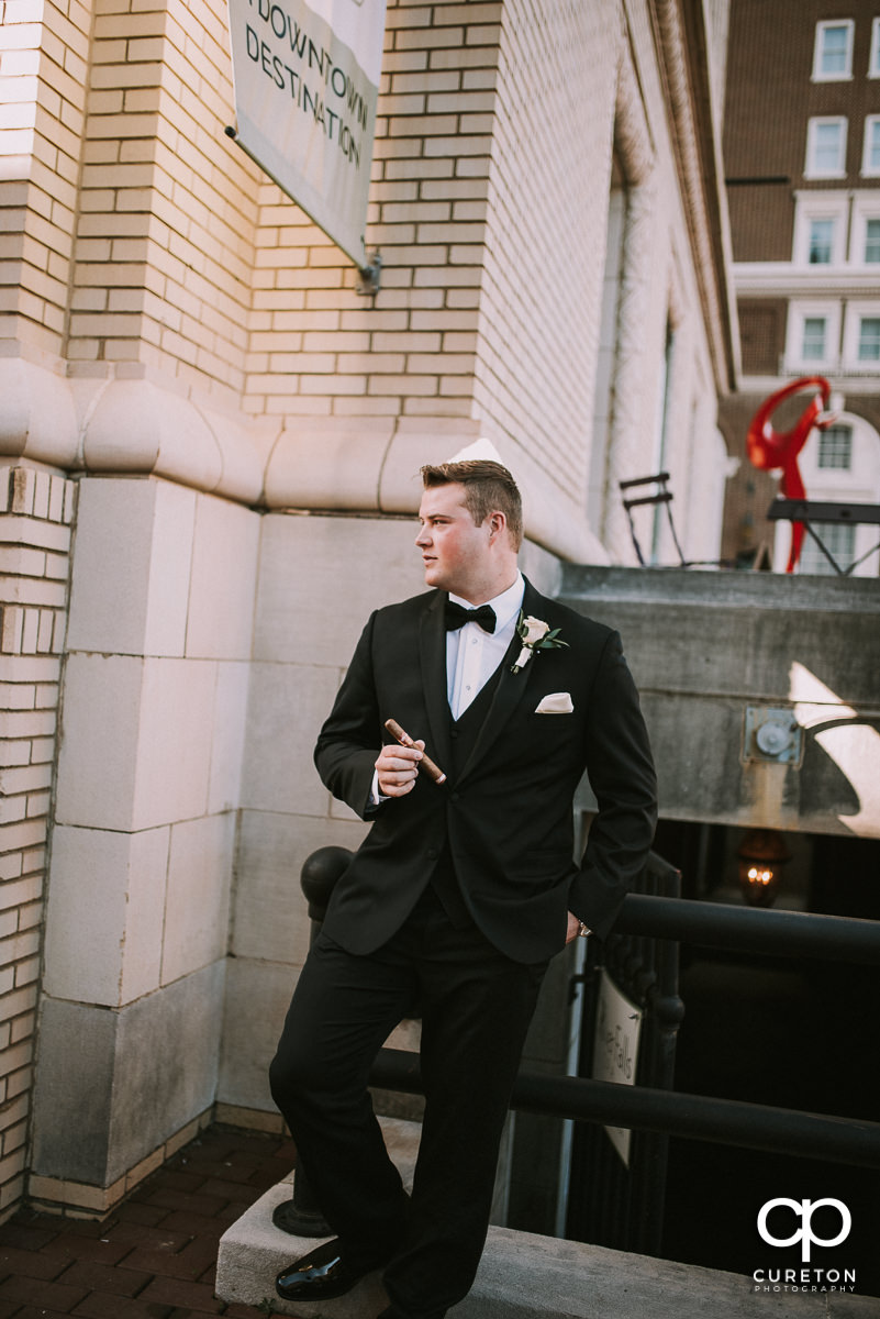 Groom smoking a cigar in front of the Westin Hotel before the wedding ceremony.