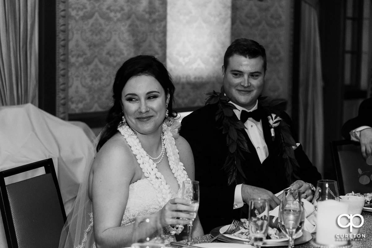 Bride and groom smiling while seated at the reception.