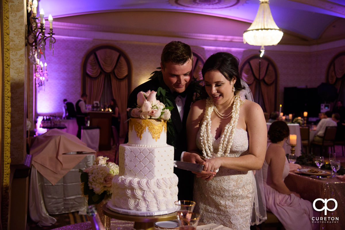 Bride and groom cutting the cake in the gold room at The Westin Poinsett reception.