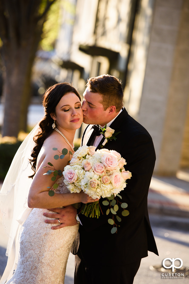 Groom kissing his bride on the cheek.