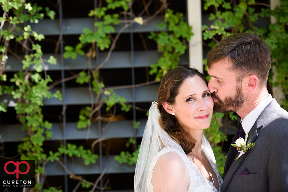 Groom kissing his bride on the cheek.