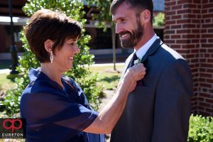 Groom's mom pinning a boutonniere on his jacket.
