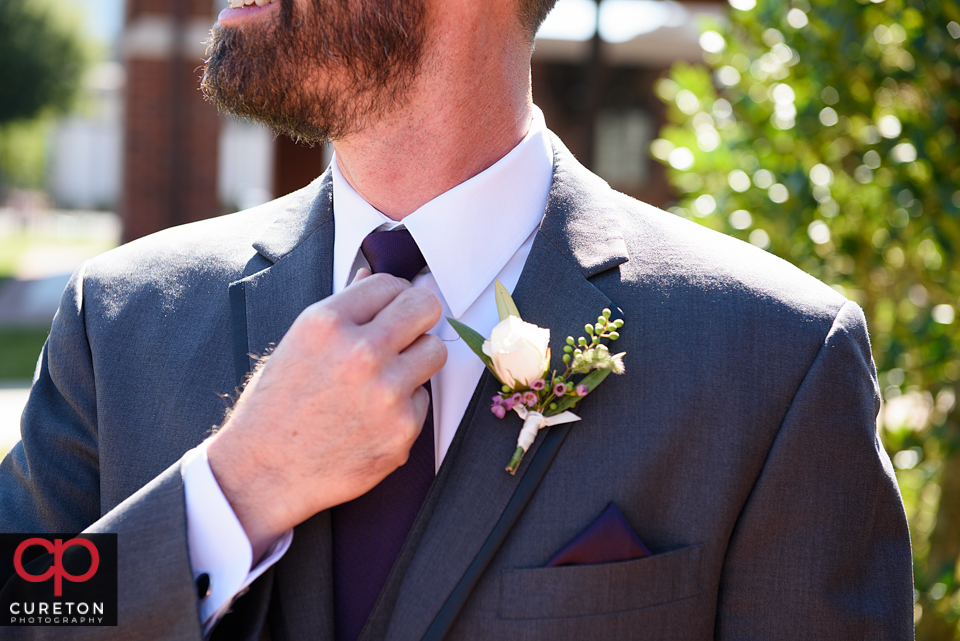 Groom fixing his tie.