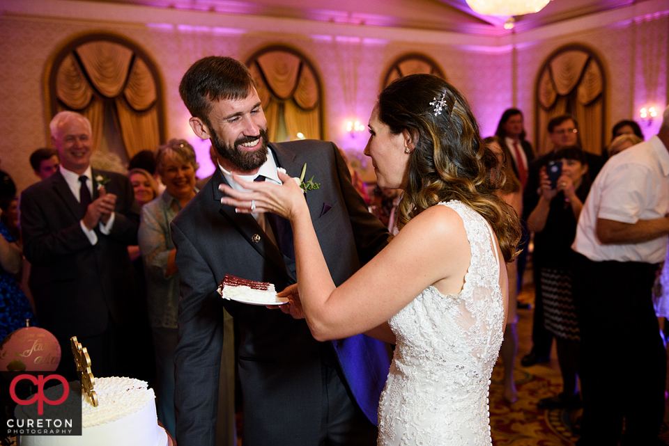 Bride and groom feeding each other wedding cake.