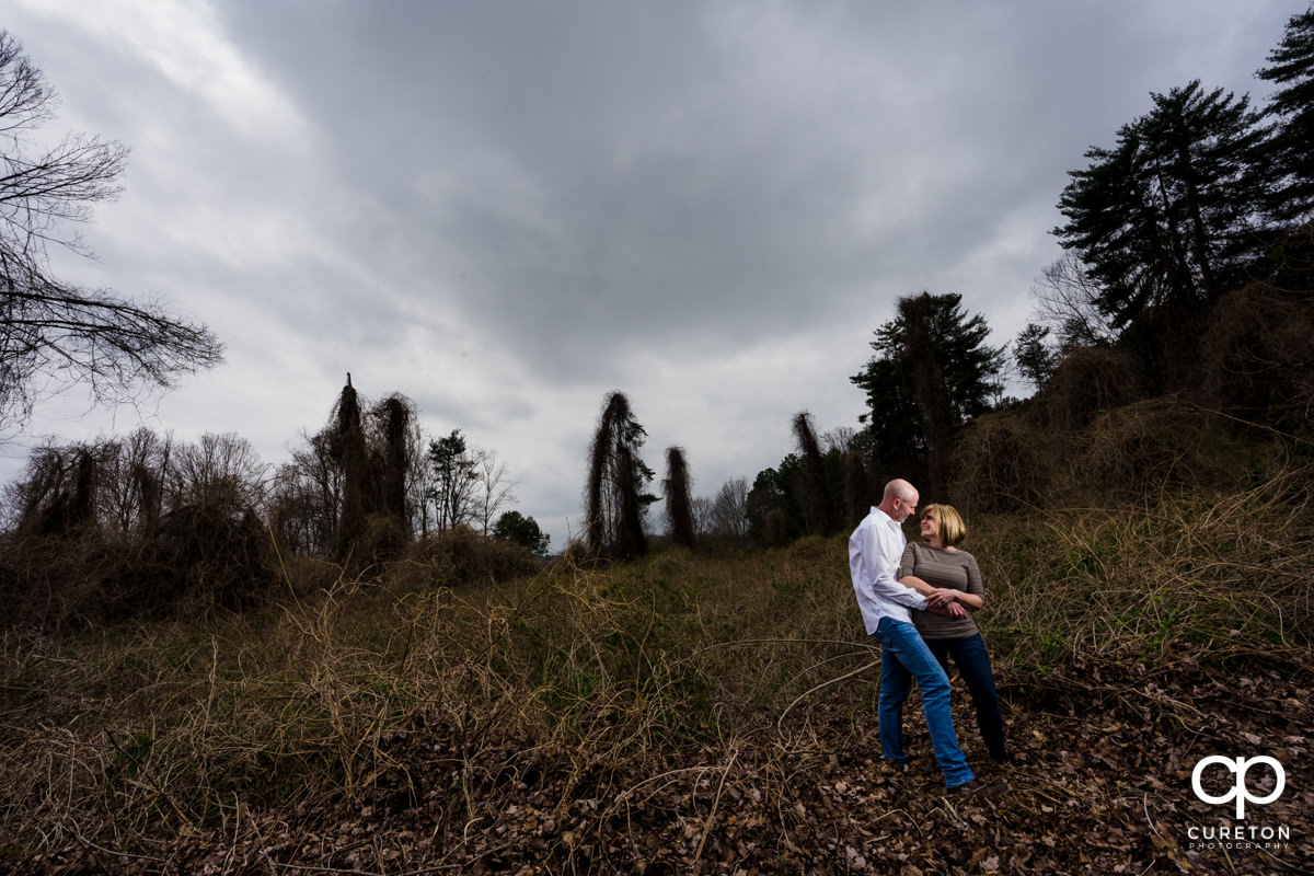 Engaged couple standing in an overgrown field during a Furman University winter Engagement session in Greenville,SC.