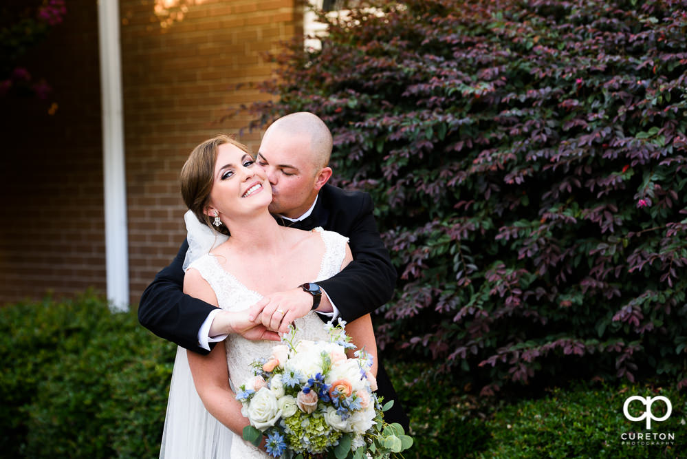Groom kissing his bride on the cheek after their wedding ceremony.