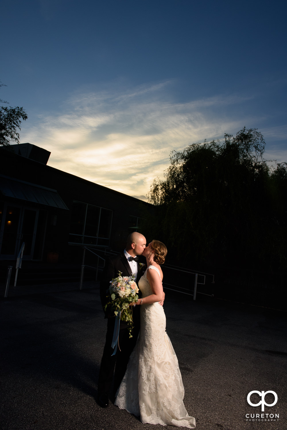 Bride and groom kissing at sunset during their wedding reception at Zen Greenville.