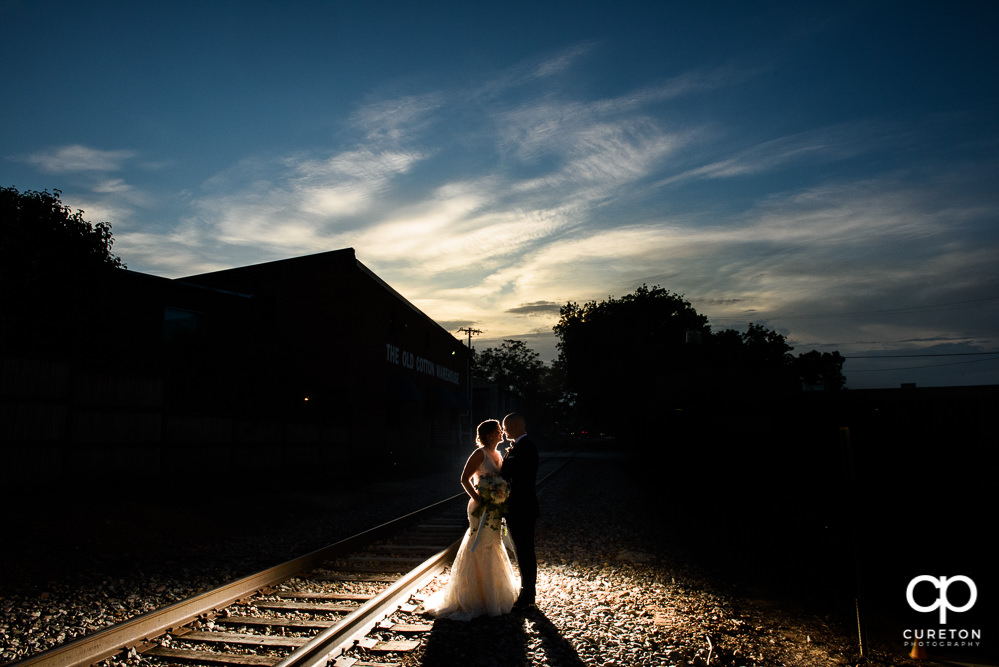 Bride and groom at sunset on the railroad tracks during their wedding reception at Zen Greenville.