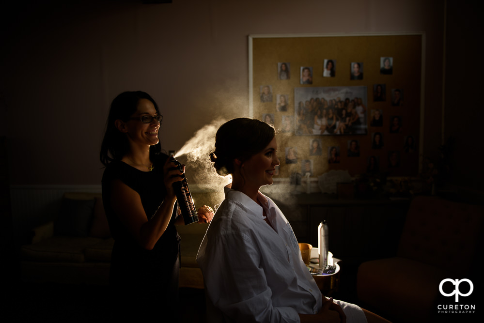 Katie Cotton spraying hairspray on the bride at her studio.