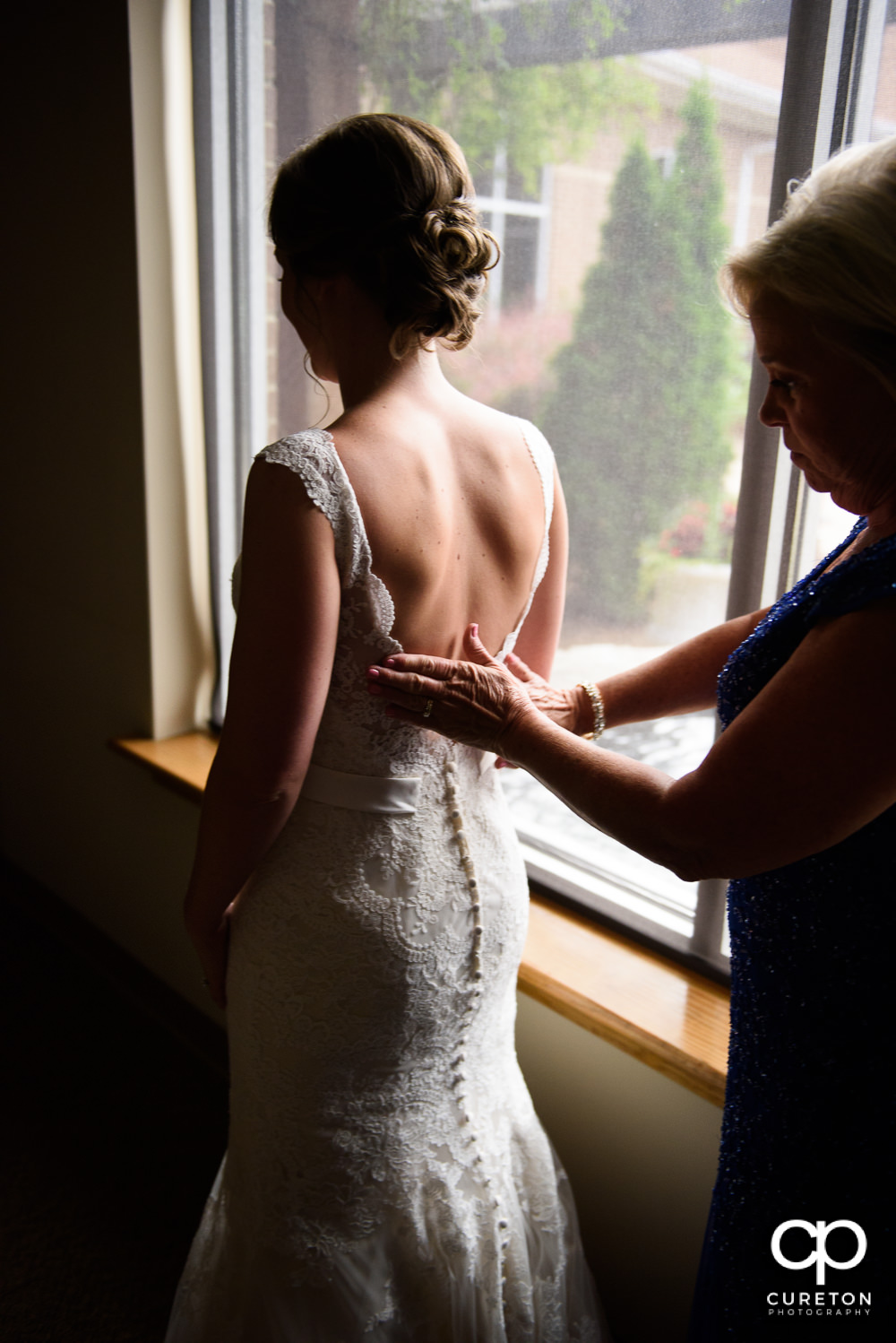 Bride's mother helping her into the dress.