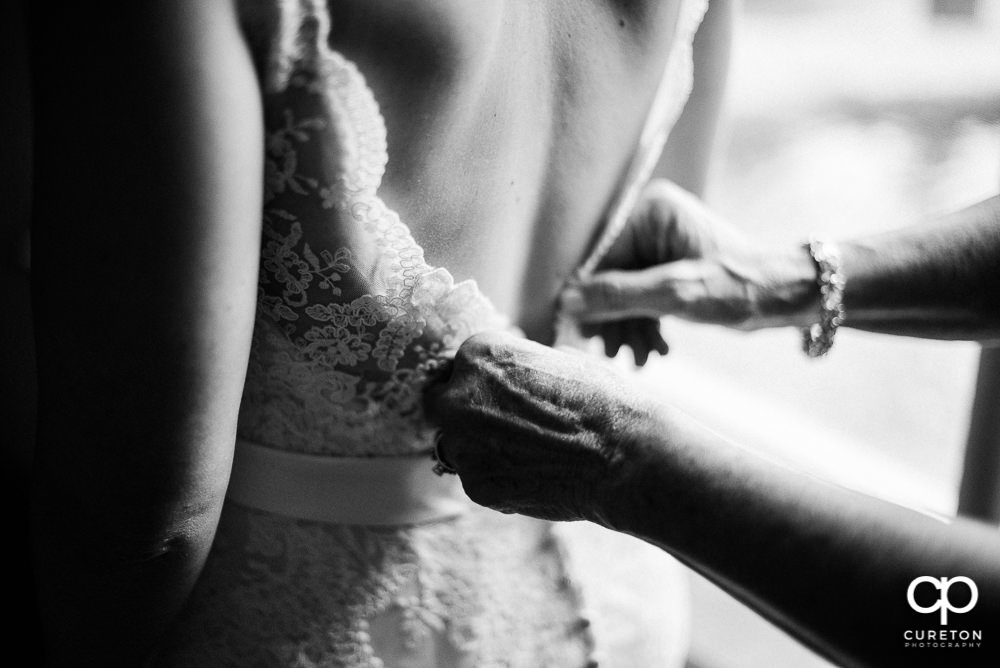Bride's mom fastening the back of the dress.