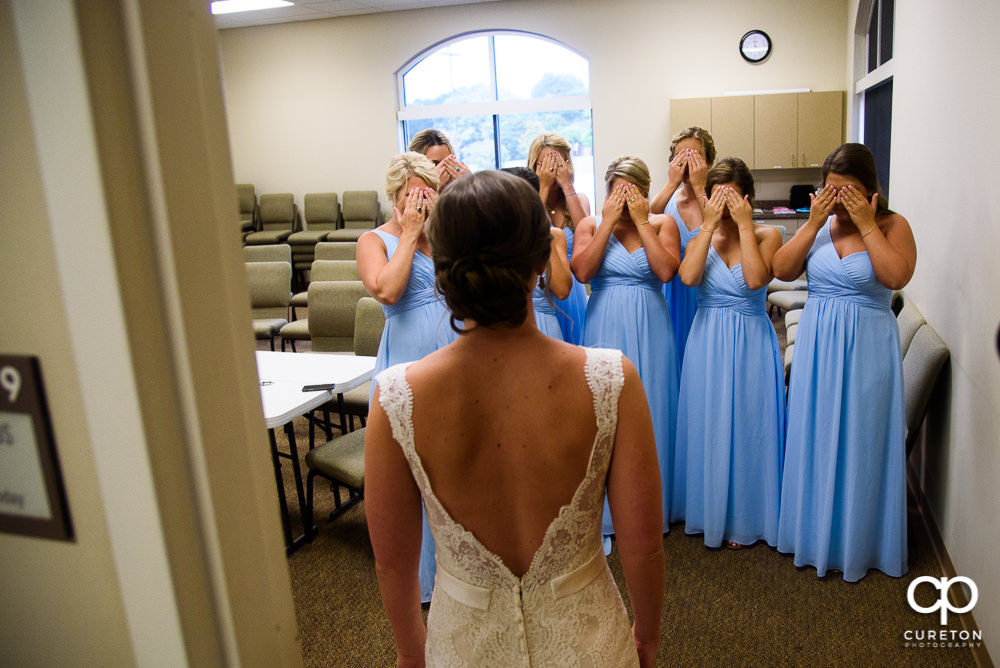 Bride revealing the dress to the bridesmaids.