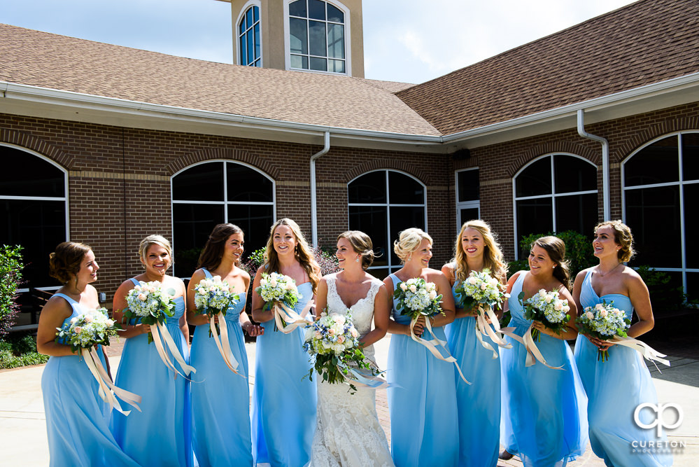Bride and bridesmaids in the courtyard at Bride having a first look with her dad in the courtyard of Covenant United Methodist Church before the wedding ceremony.