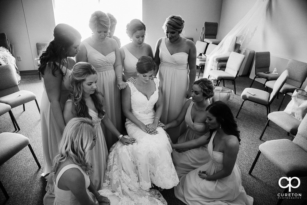 The bridesmaids praying with the bride.