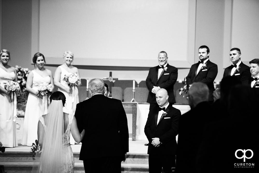 Bride and her father walking down the aisle with the groom's reaction.